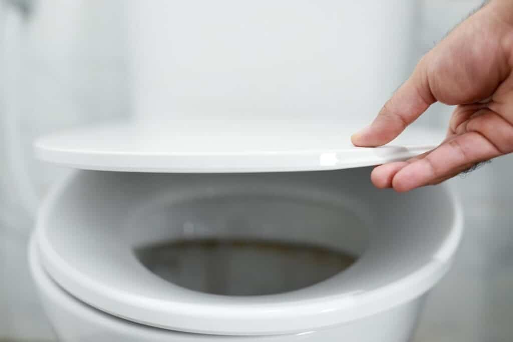 man s hand opening toilet lid 109549 3592 man s hand opening toilet lid 109549 3592