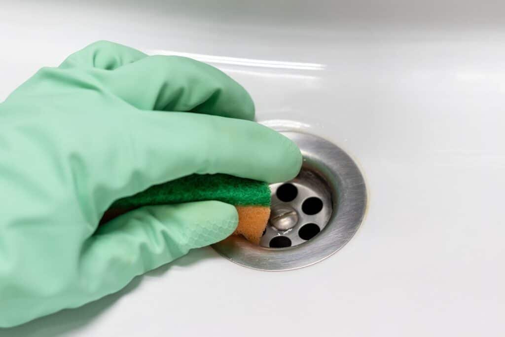 hand rubber glove with sponge rubs wet dirty sink near drain hole 327904 163